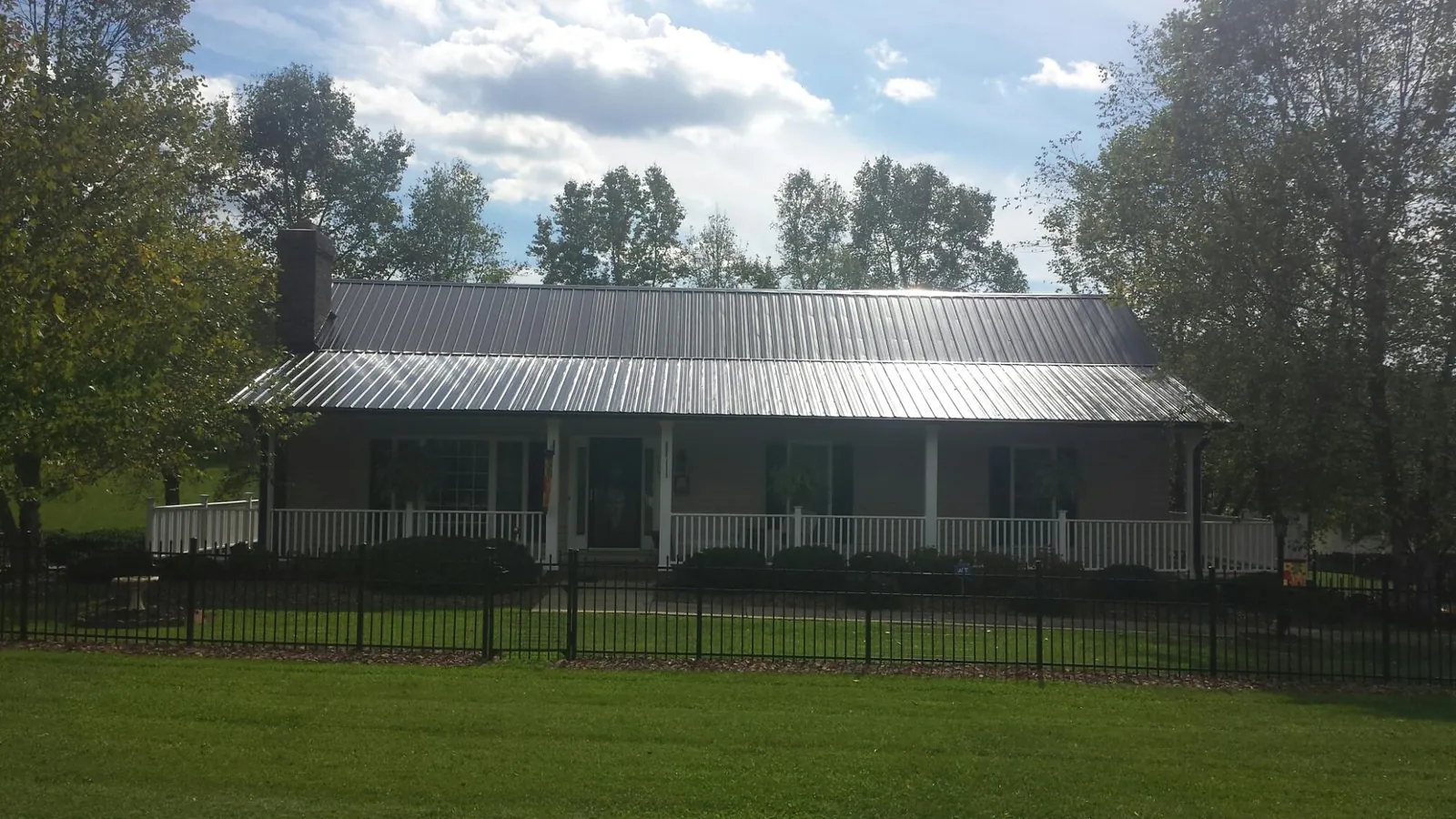 Gray metal roof on a brick ranch with a full width front porch — Gutter Guard Installation work by our crew in Milano
