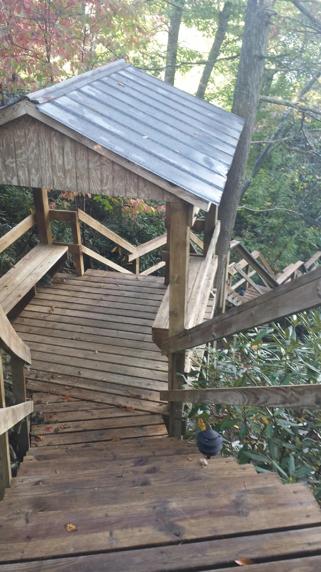 Metal roofed shelter over wooden steps on a wooded walkway — Skylight Repair & Installation work by our crew in Milano