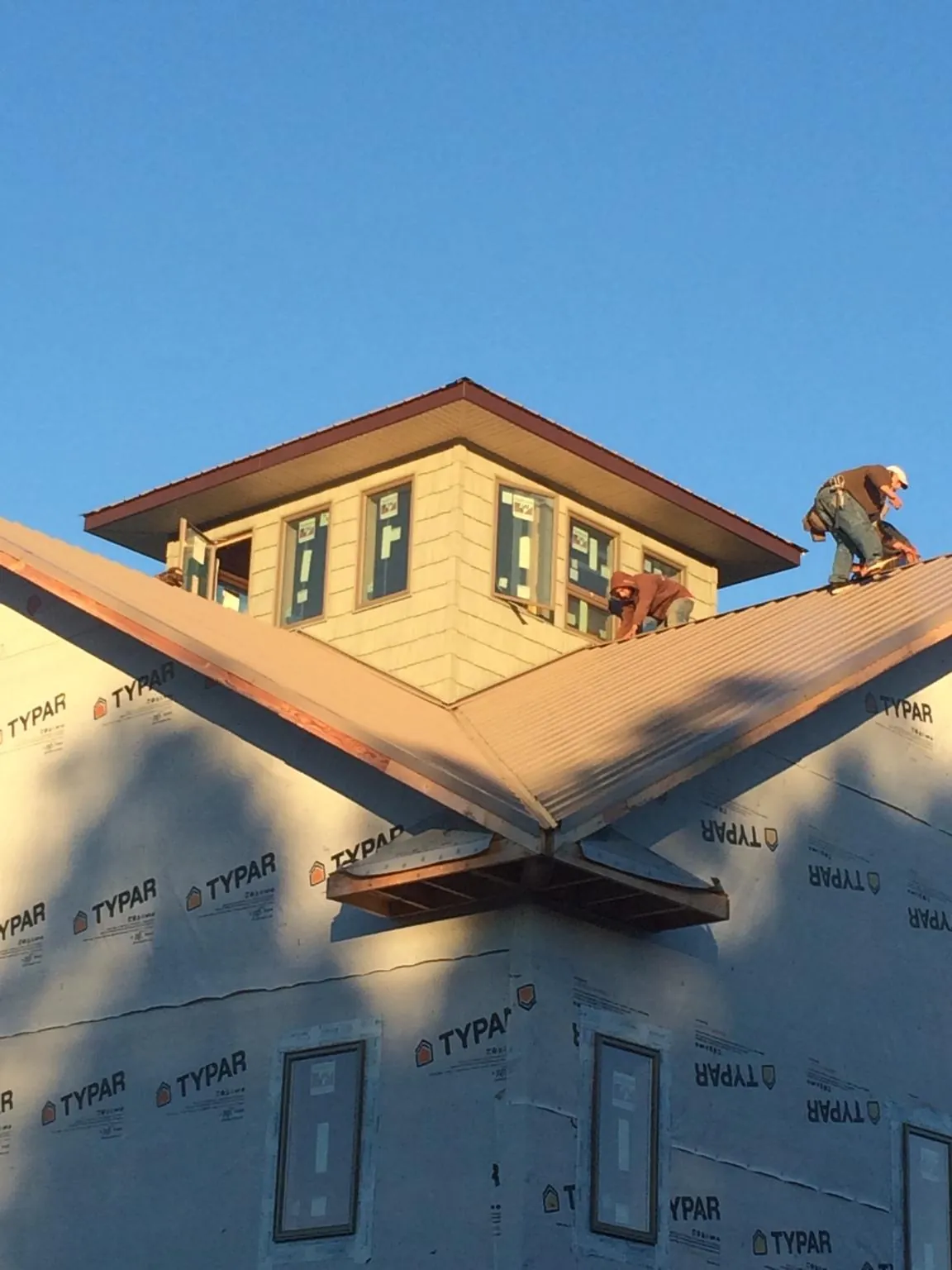 Roofers working around a rooftop cupola on a new metal roof at sunset — Roof Waterproofing in Milano by Roofing Brothers